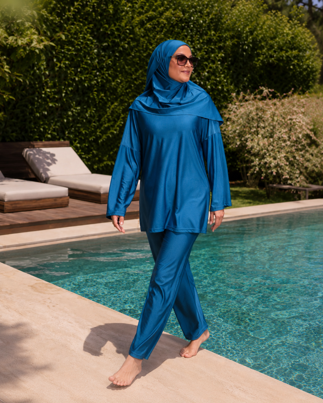 Femme en burkini RIMAYA bleu roi marchant au bord de la piscine